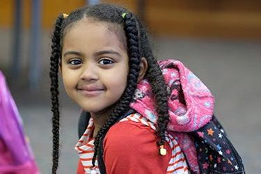 A young student smiles for a photo in a classroom